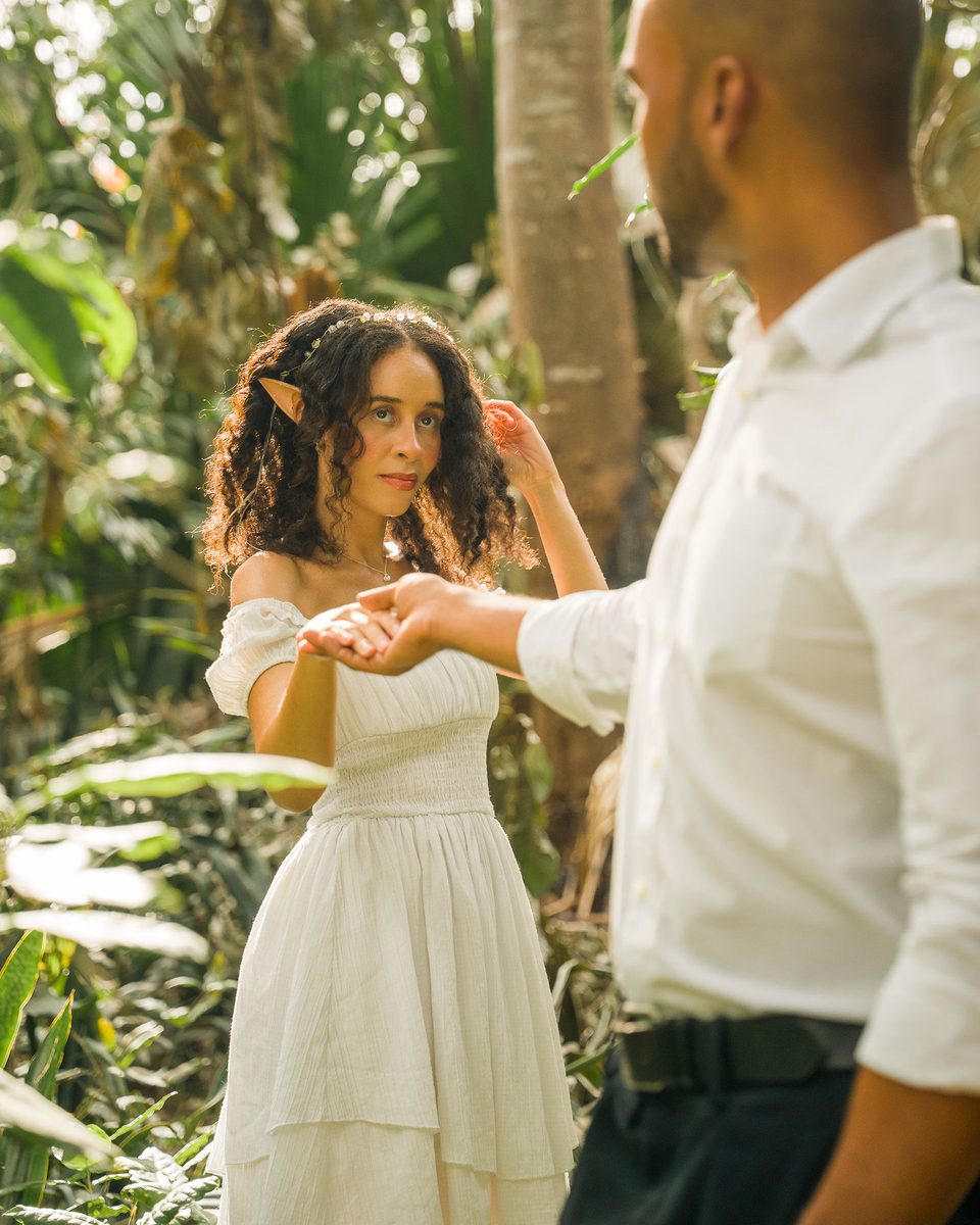 The two of them dancing among palms, hands joined, mid-turn.