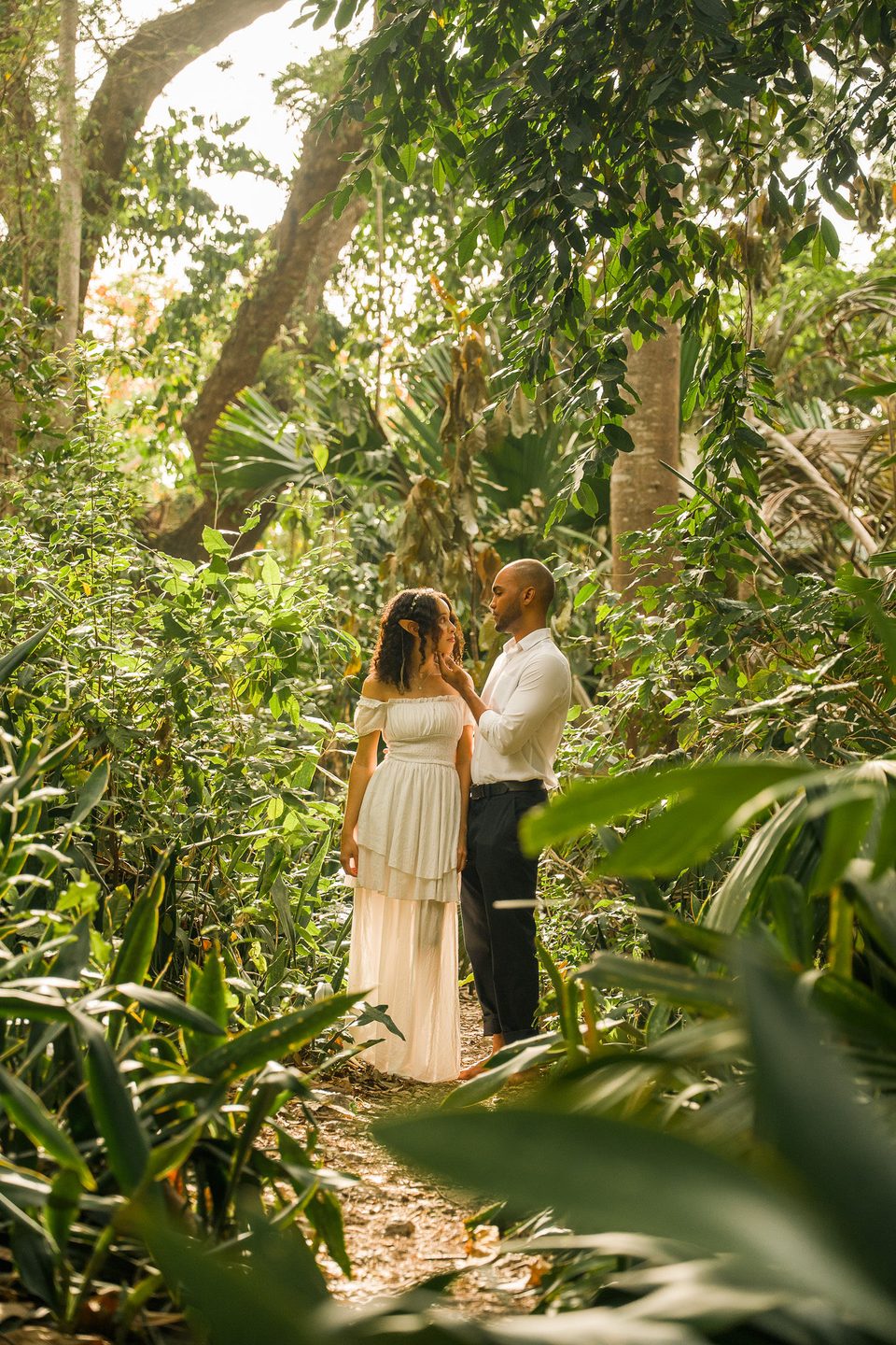The couple standing face to face on a narrow path through dense green garden.