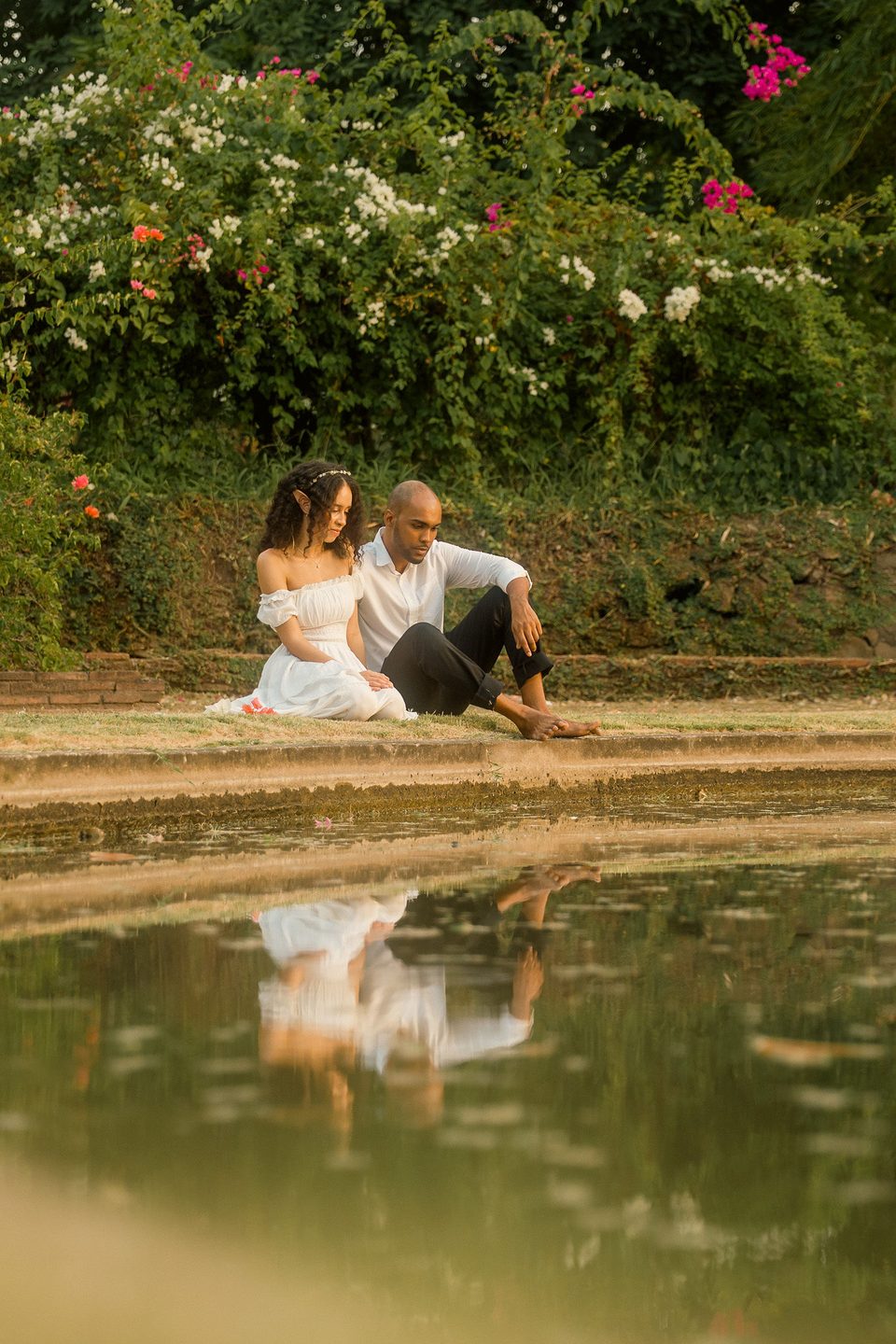 At the edge of the lily pond, mirrored in the water.