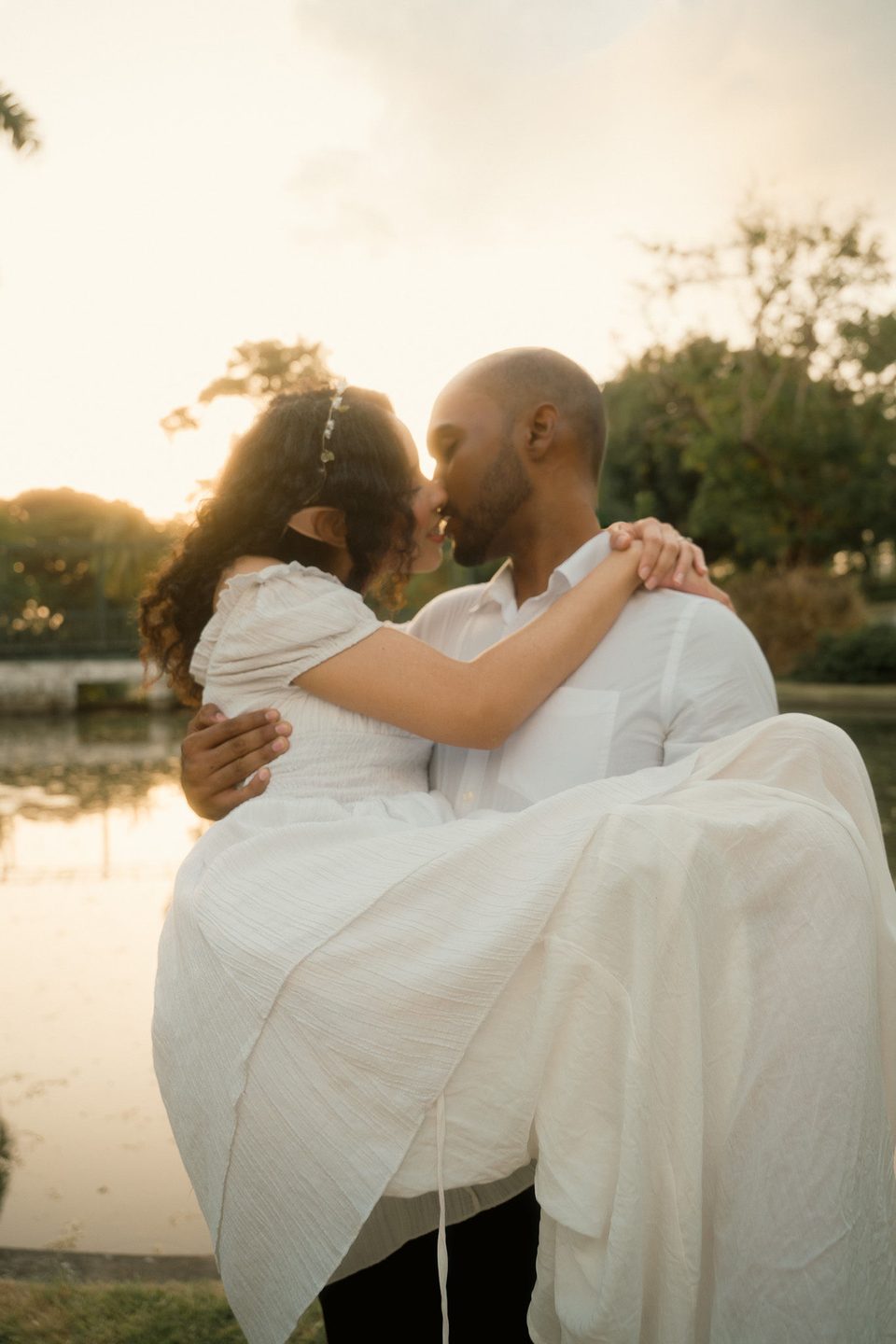 Carrying her by the water at sunset, foreheads together.
